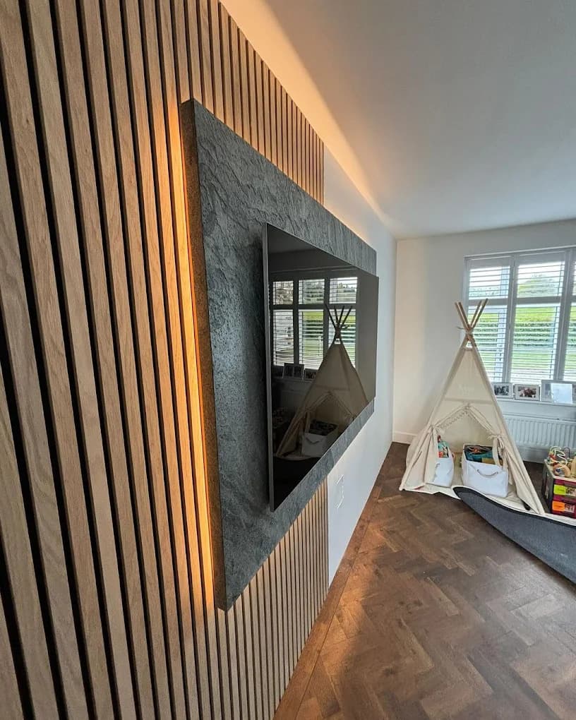 Wall-mounted TV on a slatted media wall with LED backlighting, installed by Bespoke AVS